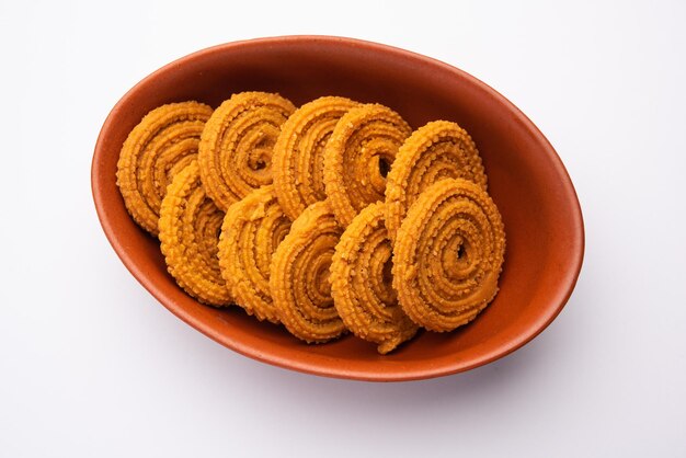 Spiral spiked Indian chakli snack, a savory fried treat, isolated on white background.
