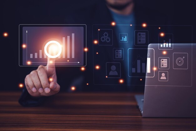 Man interacting with glowing digital analytics icons next to a laptop, showing data dashboards and tech performance data.