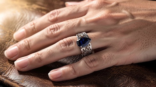 Close-up of a hand wearing a silver ring on a dark background.