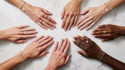 Multiple hands with rings laid out together on a white surface.